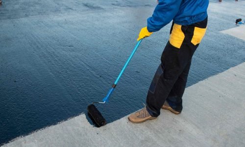 a-worker-applying-bitumen-based-waterproofing-material-on-surface